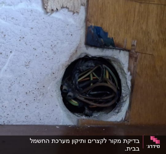 חוטי חשמל חשופים בקיר עם חור עגול